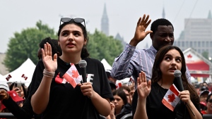 New Canadians raise their hands as they say the Oath of Citizenship, during a ceremony in the Canada Day noon show at LeBreton Flats in Ottawa, on Saturday, July 1, 2023. THE CANADIAN PRESS/Justin Tang