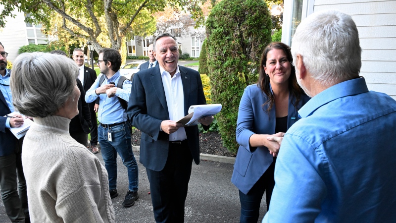 Quebec Premier Francois Legault, centre, smiles as Coalition Avenir Quebec candidate Marie Anik Shoiry meets electors while as they campaign for an upcoming byelection on Monday, September 25, 2023 in Quebec City. THE CANADIAN PRESS/Jacques Boissinot