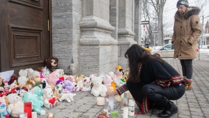 A woman lights a candle at a memorial outside a church close to the site of a daycare centre in Laval, Que, Thursday, February 9, 2023, where a bus crashed into the building killing two children. The parents of one of the two children who died have paid tribute to their four-year-old daughter in a letter sent to Quebec media. THE CANADIAN PRESS/Graham Hughes