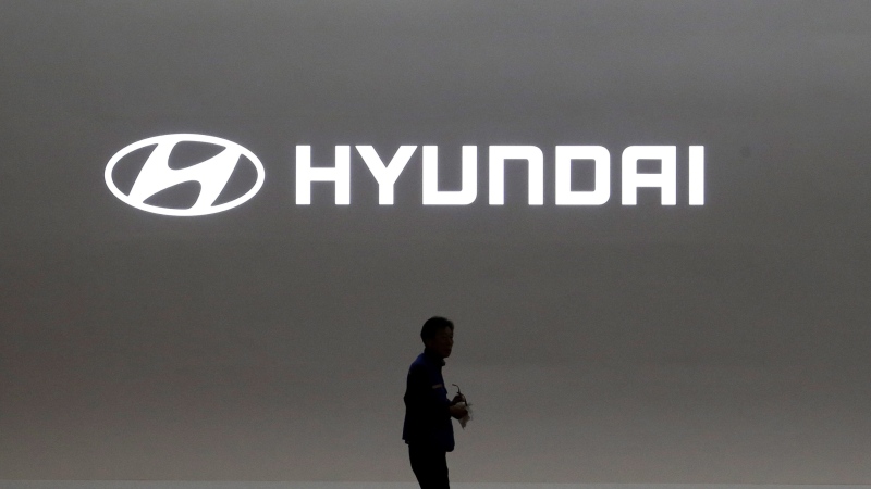 In this March 28, 2019, file photo a journalist passes by the logo of Hyundai Motor during a media preview of the Seoul Motor Show in Goyang, South Korea. (AP Photo/Ahn Young-joon, File)