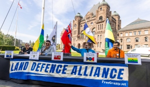 Members of the Land Defence Alliance, left to right, Cecilia Begg from Kitchenuhmaykoosib Inninuwug, Chief Chris Moonias of Neskantaga First Nation, Chief Rudy Turtle of Grassy Narrows First Nation and deputy chief Stanley Anderson of Wapekeka First Nation sit at a formal table set up outside the Legislature ready to meet with Premier Ford seeking his signature on a declaration of respect for their rights on the lawn of Queen's Park in Toronto on Tuesday, September 26, 2023. (THE CANADIAN PRESS/Carlos Osori)