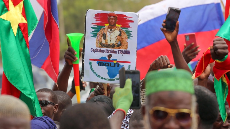 Supporters of Burkina Faso coup leader Capt. Ibrahim Traore gather outside the National Assembly waving Burkina and Russian flags as Traore was appointed Burkina Faso's transitional president in Ouagadougou, Burkina Faso, Oct. 14, 2022. (AP Photo/Kilaye Bationo)