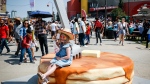 A young girl sits on a stack of pancakes for the hundredth anniversary of the Stampede pancake breakfast on Family Day at the Calgary Stampede parade in Calgary, Sunday, July 9, 2023.