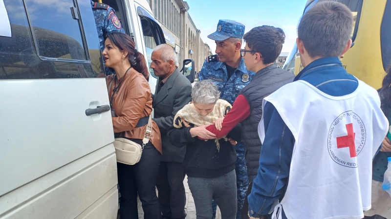 An elderly refugee being helped onto a bus that will take her to her new accommodations in Armenia's northern Tavush province (Neil Hauer for CTV News)