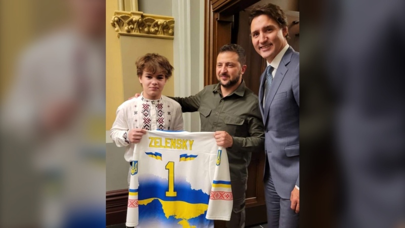 Ukrainian student and hockey player Maksym Shtepa, presents the President of Ukraine Vlodymyr Zelensky with a jersey, alongside Prime Minister Justin Trudeau. Six Ukrainian students were able to start school on Friday in Quebec City after obtaining their English eligibility certificates from the government.