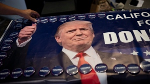 An attendee grabs a campaign button supporting former President Donald Trump at the California Republican Party Convention in Anaheim, Calif., Saturday, Sept. 30, 2023. (AP Photo/Jae C. Hong)
