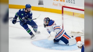 Vancouver Canucks' Quinn Hughes, back left, scores his first goal against Edmonton Oilers goalie Stuart Skinner during the second period of a pre-season NHL hockey game in Vancouver, B.C., Saturday, Sept. 30, 2023. THE CANADIAN PRESS/Darryl Dyck