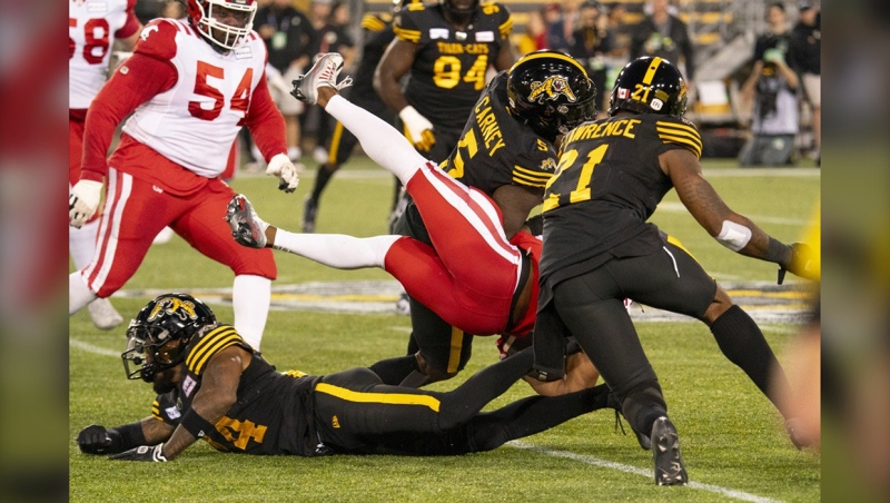 Calgary Stampeders running back Ka'Deem Carey (35) is tackled by Hamilton Tiger Cats defensive end Malik Carney (5) and Hamilton Tiger Cats linebacker Simoni Lawrence (21) during first half CFL football game action in Hamilton, Ont., Saturday, Sept. 30, 2023. THE CANADIAN PRESS/Peter Power