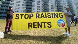 Two young people hold a sign that reads, 'Stop Raising Rents,' at an apartment building in northwest Toronto. (Sean Leathong/CTV News)