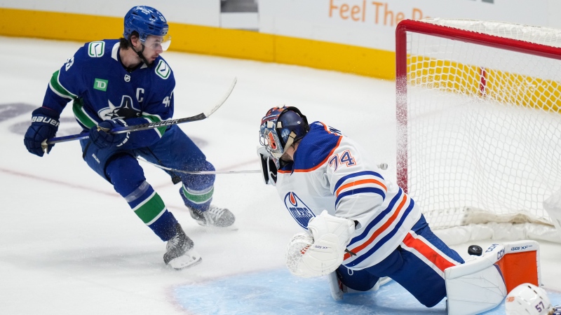 Vancouver Canucks' Quinn Hughes, back left, scores his first goal against Edmonton Oilers goalie Stuart Skinner during the second period of a preseason NHL hockey game in Vancouver, B.C., Saturday, Sept. 30, 2023. THE CANADIAN PRESS/Darryl Dyck