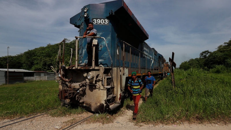 In this June 25, 2019 photo, migrants walk alongside a freight train headed north near Salto del Agua, Mexico. (AP Photo/Marco Ugarte)