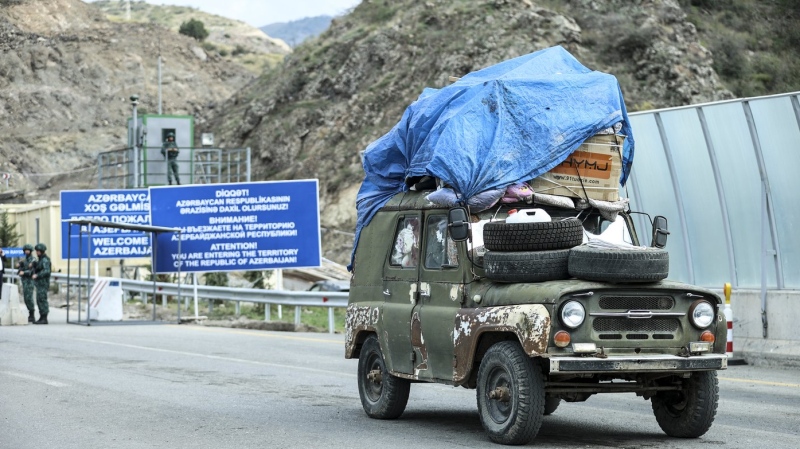Sergey Astsetryan, an ethnic Armenian resident of Nagorno-Karabakh, drives his Soviet-made vehicle past Azerbaijani border guard servicemen after been checked at the Lachin checkpoint on the way from Nagorno-Karabakh to Armenia, in Azerbaijan, Sunday, Oct. 1, 2023. (AP Photo/Aziz Karimov)