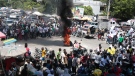 Protesters walk around burning tires during a protest against insecurity in Port-au-Prince, Haiti, Sunday, Sept. 17, 2023. (AP Photo/Odelyn Joseph)