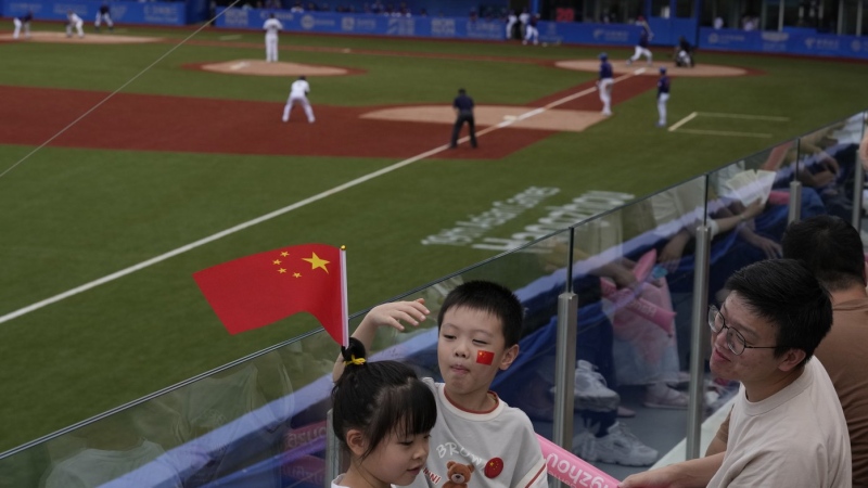 Chinese children with Chinese national flag and decals attend a stage group round B Baseball Men game between Taiwan and Hong Kong for the 19th Asian Games in Hangzhou, China on Tuesday, Oct. 3, 2023. (AP Photo/Ng Han Guan)