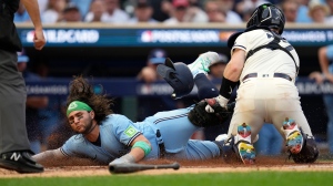 Toronto Blue Jays' Bo Bichette, left, is tagged out at home plate by Minnesota Twins catcher Ryan Jeffers on a fielder's choice after an infield single by Kevin Kiermaier during the fourth inning in Game 1 of an AL wild-card baseball playoff series Tuesday, Oct. 3, 2023, in Minneapolis. (AP Photo/Abbie Parr)