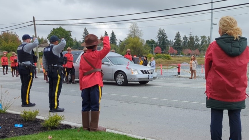 A child wearing an RCMP costume salutes the funeral procession for Const. Rick O'Brien in Langley, B.C., on Oct. 4, 2023. 