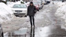 A pedestrian tries to avoid walking through flooded water in Ottawa on Saturday, Feb. 20, 2016. Temperatures rose above 0 C in Ottawa that day. THE CANADIAN PRESS/Justin Tang
