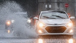A motorist makes their way along a street through pooling water during heavy rain in Montreal, Saturday, October 7, 2023. Environment Canada has issued a rainfall warning for the province. THE CANADIAN PRESS/Graham Hughes