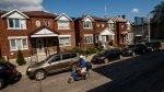 A person rides a scooter by a row of houses in Toronto on Tuesday July 12, 2022. THE CANADIAN PRESS/Cole Burston 