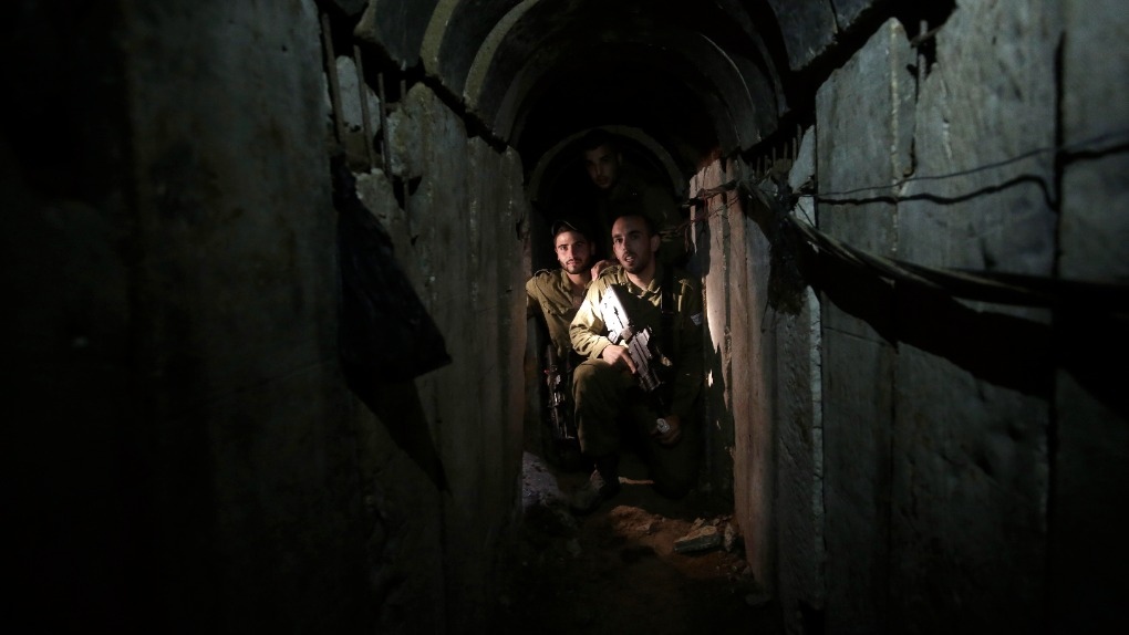 Israeli soldiers walk through a tunnel discovered 