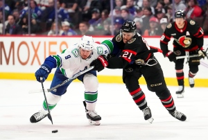 Ottawa Senators right wing Mathieu Joseph (21) tries to push Vancouver Canucks centre J.T. Miller (9) off the puck during third period NHL hockey action in Ottawa on Thursday, Nov. 9, 2023. (Sean Kilpatrick/THE CANADIAN PRESS)