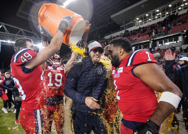 Montreal Alouettes linebacker Frederic Chagnon (49) douses Alouettes head coach Jason Maas, centre, after defeating the Toronto Argonauts in CFL Eastern Conference finals football action in Toronto on Saturday, November 11, 2023. THE CANADIAN PRESS/Nathan Denette