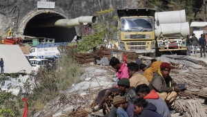 People sit near the site of an under-construction road tunnel that collapsed trapping 41 workers in Silkyara in the northern Indian state of Uttarakhand, Wednesday, Nov. 22, 2023. (AP Photo)