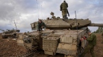Israeli soldiers work on a tank at an army staging area near Israel's border with Gaza, southern Israel, Monday, Nov. 27, 2023. (AP Photo/Ohad Zwigenberg)