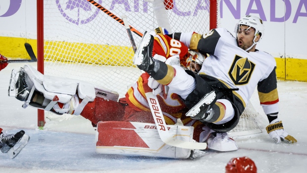 Vegas Golden Knights forward William Carrier, right, slams into Calgary Flames goalie Daniel Vladar during first period NHL hockey action in Calgary, Alta., Monday, Nov. 27, 2023. THE CANADIAN PRESS/Jeff McIntosh