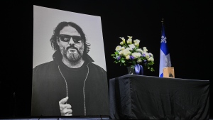 A photo and flowers are shown on the stage during an event paying tribute to the late Karl Trembly, lead singer with Les Cowboys Fringants, in Montreal, Tuesday, November 28, 2023. THE CANADIAN PRESS/Graham Hughes