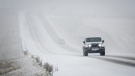 A vehicle travels along a snow-covered Highway 22, also known as the Cowboy Trail, near Cremona, Alta., Monday, Oct. 23, 2023. THE CANADIAN PRESS/Jeff McIntosh
