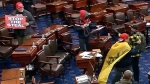 This image from Senate Television video shows Ryan Joseph Orlando, top right, looking at papers on a lectern on the Senate floor on Jan. 6, 2021, at the U.S. Capitol in Washington. Orlando, 28 of Arlington, Va., was arrested Wednesday, Nov. 29, 2023, on charges that he stormed the U.S. Capitol while wearing a Captain America backpack and stole items from senators' desks on the Senate floor during the Jan. 6, 2021, riot, court records show.(Senate Television via AP)