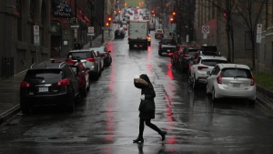 A pedestrian tries to shield herself from heavy wind and rain in Halifax on Friday, December 23, 2022. THE CANADIAN PRESS/Darren Calabrese