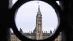 The Parliament Hill Peace Tower is framed in an iron fence on Wellington Street in Ottawa on Thursday, March 12, 2020. (THE CANADIAN PRESS/Sean Kilpatrick)