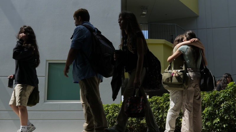 A pair of Miami Arts Studio students hug as others walk between classes, on World Mental Health Day, Tuesday, Oct. 10, 2023, at the public 6th-12th grade magnet school, in Miami. (AP Photo/Rebecca Blackwell)