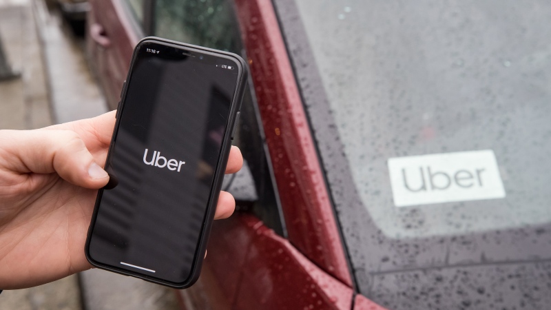 The Uber app is seen on an iPhone near a driver's vehicle after the company launched service, in Vancouver, Friday, Jan. 24, 2020. THE CANADIAN PRESS/Darryl Dyck