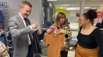 Minister of Education Jeremy Cockrill (left) and Luther College High School students Lila Gelowitz (centre) and McKenna Glover-Quartui fold donated clothes at the YWCA in downtown Regina. (Gareth Dillistone/CTV News)