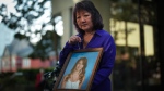 Carol Todd holds a photo of her late teenage daughter, Amanda Todd, who died by suicide in 2012, and the necklace she was wearing in the school photo, outside B.C. Supreme Court after sentencing for the Dutch man who was accused of extorting and harassing her daughter, in New Westminster, B.C., on Friday, October 14, 2022. TTHE CANADIAN PRESS/Darryl Dyck