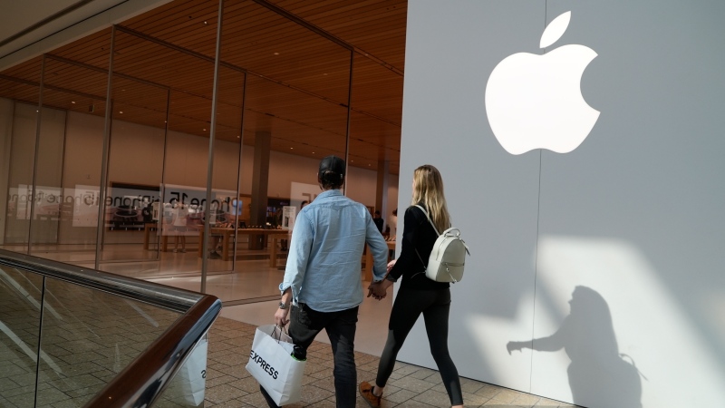 File - People walk by an Apple store Oct. 20, 2023, in Denver. (AP Photo/Brittany Peterson, File)