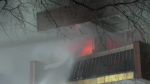 Water is sprayed on visible flames inside 10745 79 Ave. NW the early morning of Jan. 26, 2024. (CTV News Edmonton / Evan Klippenstein)
