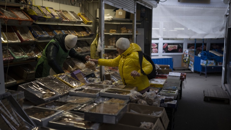A woman buys from a vendor at a market in Kyiv, Ukraine, Monday, Jan. 30, 2023. (AP Photo/Daniel Cole, File)