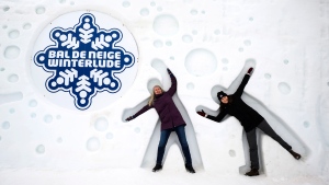 Kelly Hanselman, left, and her daughter Kate pose for a photo in human shaped cutouts in the side of the ice slides hill, at Snowflake Kingdom during the first weekend of Winterlude, in Gatineau, Que. on Saturday, Feb. 3, 2024.  (Justin Tang/THE CANADIAN PRESS)