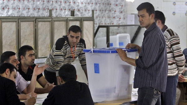 Election workers stand with ballot boxes and ballots cast by those entitled to vote early, at a counting center in Ramadi, Iraq, Saturday, March 6, 2010. (AP / Khalid Mohammed)