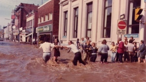 A man helps people at Main & Water Sts. during the 1974 Galt flood. (Source: City of Cambridge)