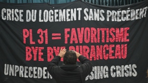A person takes a photo of a banner during a demonstration against the Quebec government's housing Bill 31 in Montreal, Saturday, February 3, 2024. THE CANADIAN PRESS/Graham Hughes