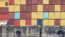 FILE: A truck drives past stacked shipping containers in the Port of Montreal, Tuesday, Sept.19, 2023.THE CANADIAN PRESS/Christinne Muschi