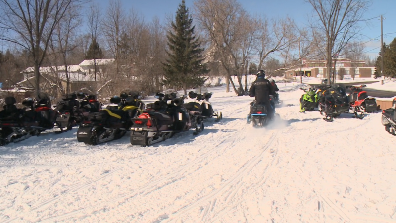 People ride snowmobiles past several other parked snowmobiles in this undated image. (Austin Lee/CTV News Ottawa)