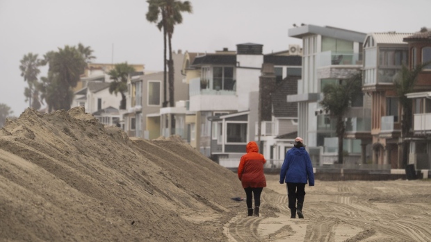 People walk next to a sand berm built by the city of Long Beach in preparation for high tide along the Peninsula in Long Beach, Calif., Monday, Feb. 19, 2024.<br><br>
The latest in a series of wet winter storms gained strength in California early Monday, with forecasters warning of possible flooding, hail, strong winds and even brief tornadoes as the system moves south over the next few days.<br><br>
(AP Photo / Damian Dovarganes)