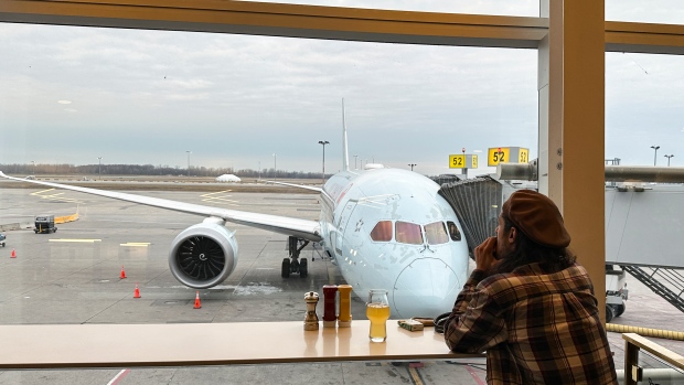 A traveller looks at an Air Canada plane as he waits for his flight at Pierre Elliott Trudeau International Airport in Montreal, Friday, Dec. 23, 2023. THE CANADIAN PRESS/Christinne Muschi