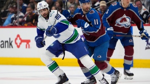 Vancouver Canucks left wing Arshdeep Bains, left, pursues the puck with Colorado Avalanche center Andrew Cogliano in the first period of an NHL hockey game Tuesday, Feb. 20, 2024, in Denver. (AP Photo/David Zalubowski)